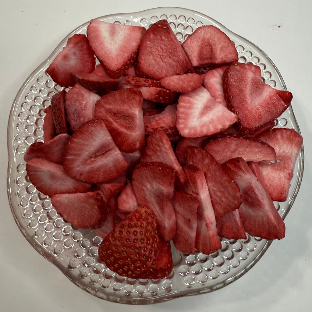 Sliced freeze dried strawberries on a decorative glass plate with a plain background