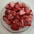 Sliced freeze dried strawberries on a decorative glass plate with a plain background