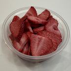 Clear plastic container filled with freeze dried strawberry slices on a white background