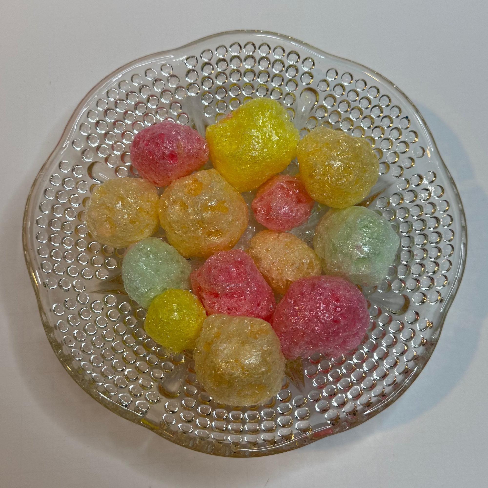 Freeze dried tropical jolly ranchers on a clear glass plate with a white background