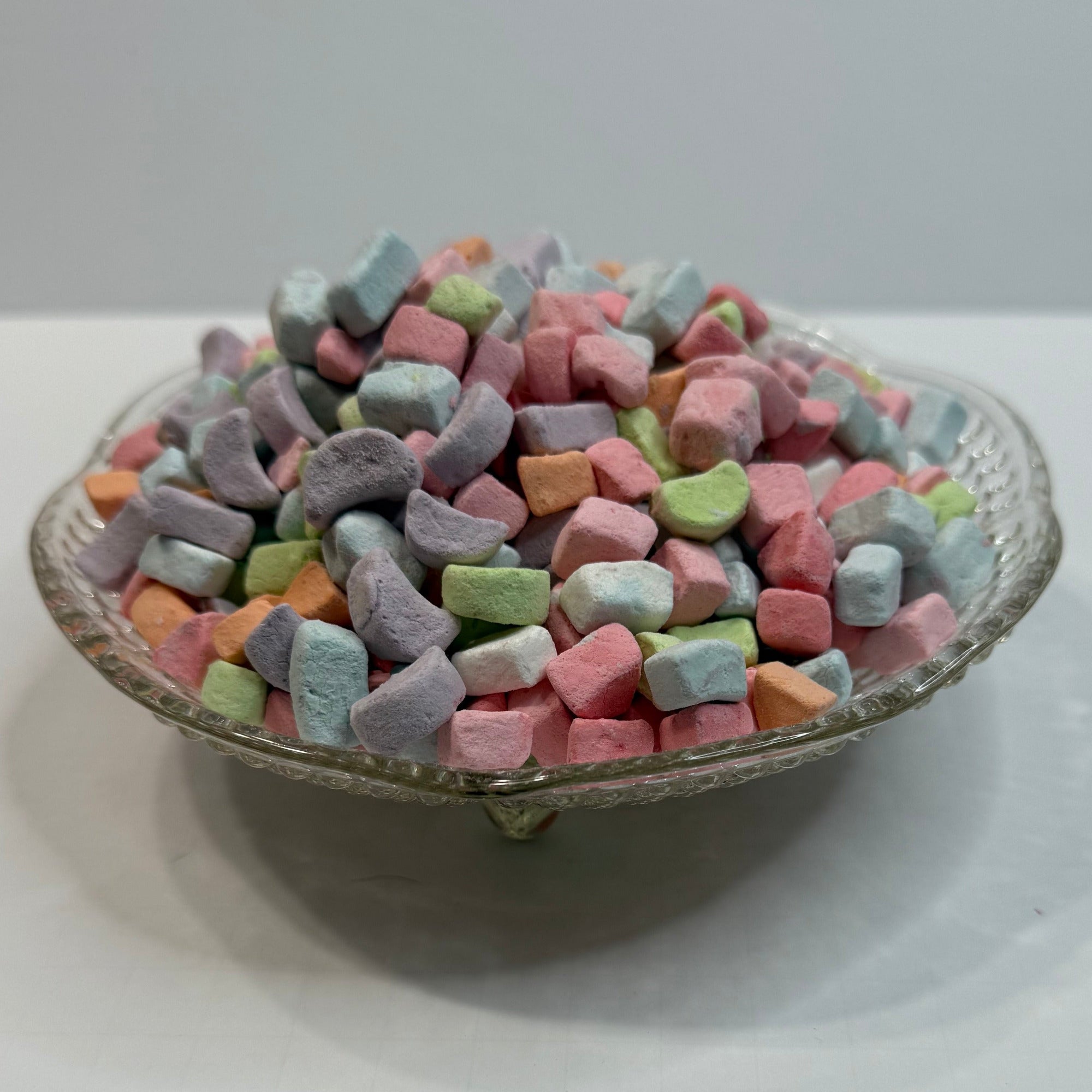 Textured glass bowl with colorful freeze dried marshmallow charms on a white background