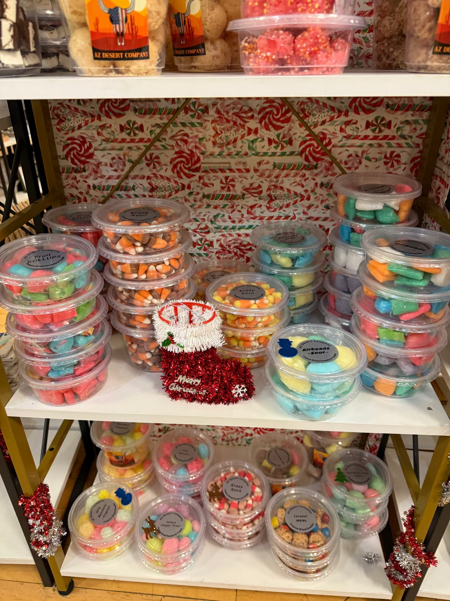 Shelf with containers of colorful freeze dried candies and a decorative background