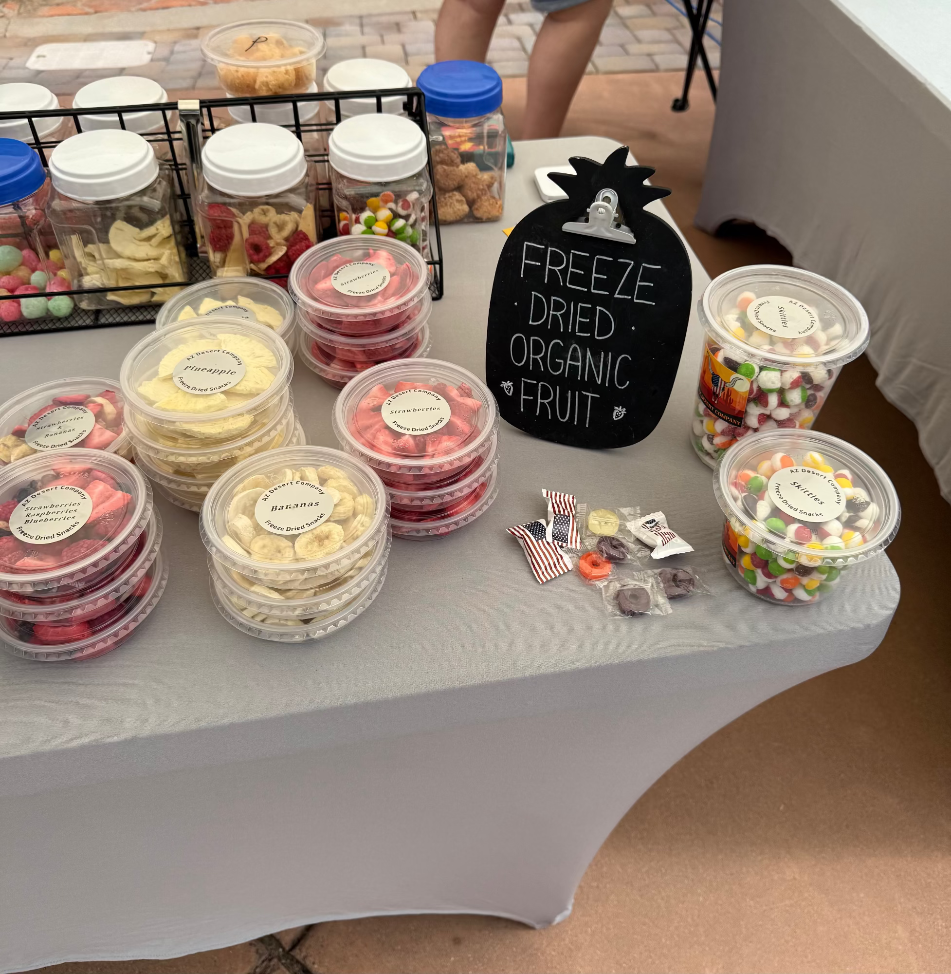 Table with containers of freeze-dried organic fruit and a sign indicating the type of product.