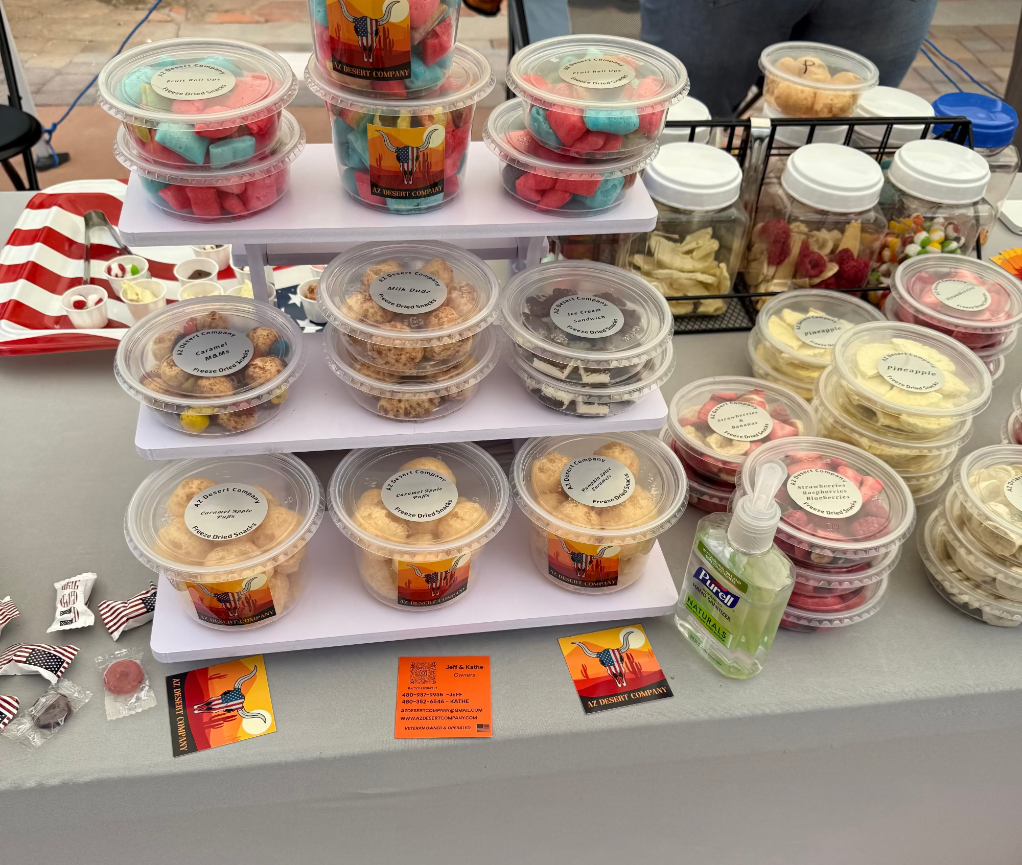 Display of various freeze dried food items in plastic containers on a table with a person partially visible.