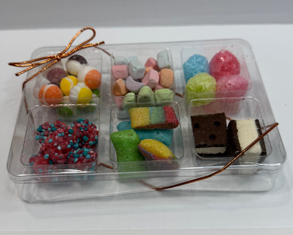 Small transparent box with colorful freeze dried snacks & candies on a white background