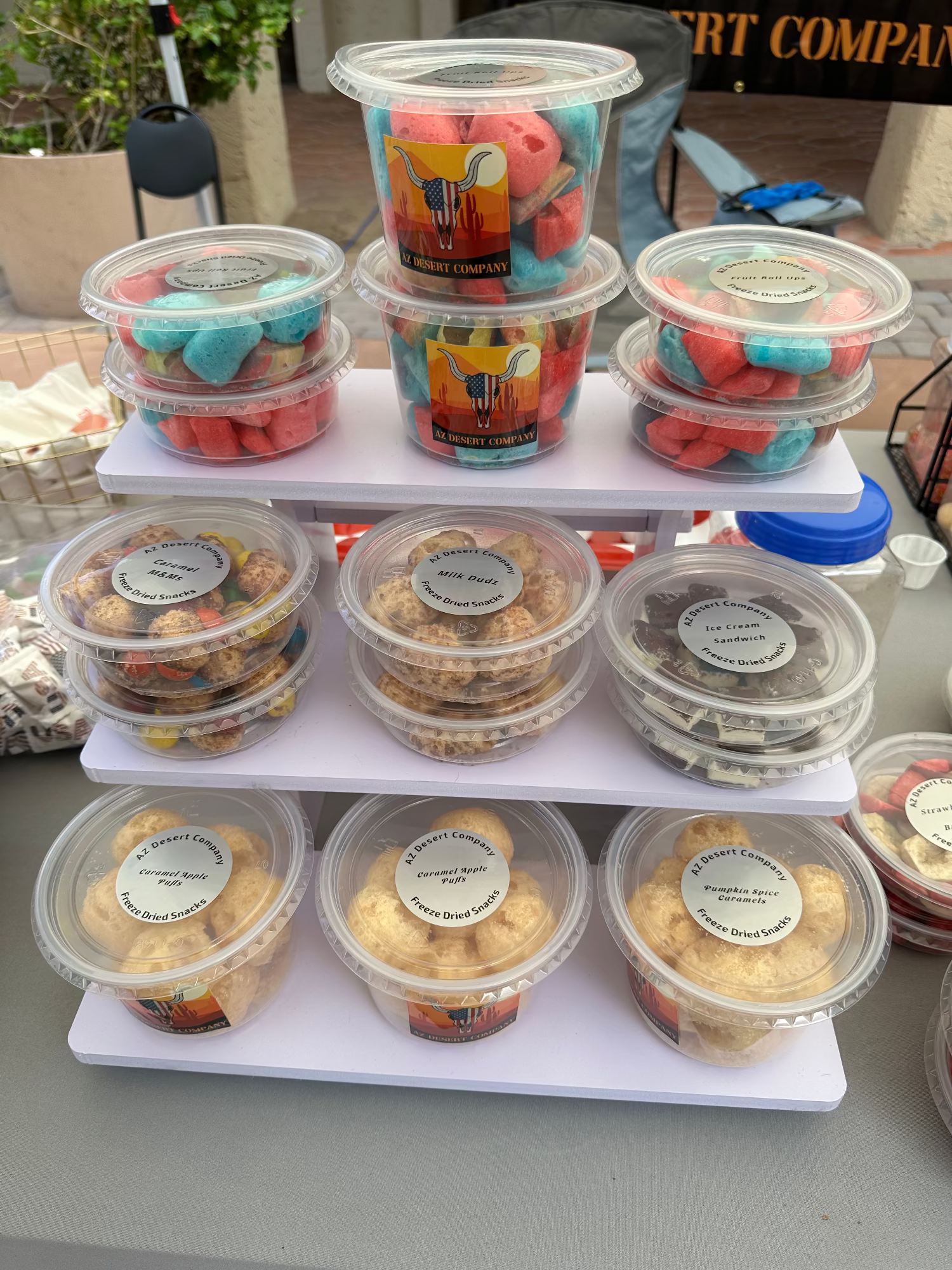 Assorted pre-packaged freeze dried desserts on a white stand with visible branding.