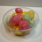 Clear bowl filled with freeze dried tropical jolly ranchers on a white surface